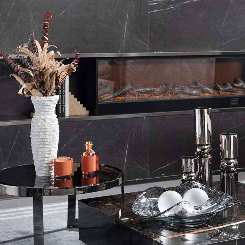 Brutalist white marble vase styled on a black marble coffee table in a modern luxury living room with a fireplace