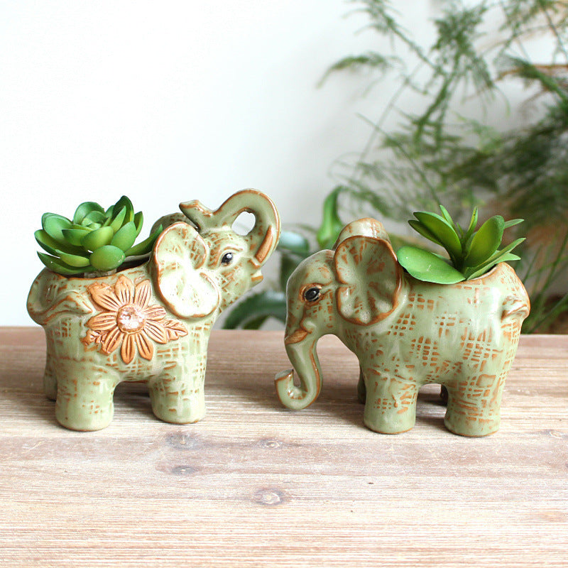 Handcrafted sage green elephant succulent planters in two sculptural poses on a wooden surface