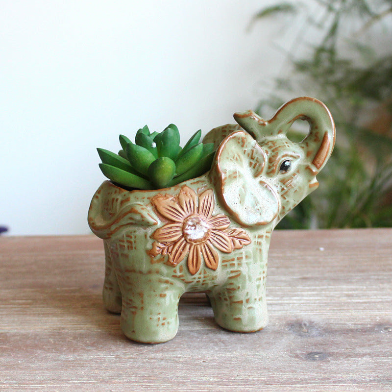 Close up of a ceramic elephant planter featuring an embossed floral design and green succulent