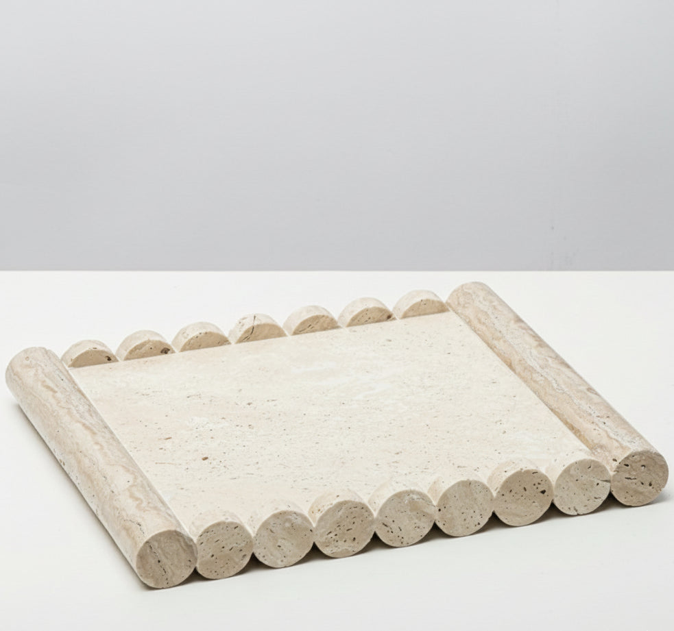 Handcrafted beige travertine tray with cylindrical scalloped edges on a white surface