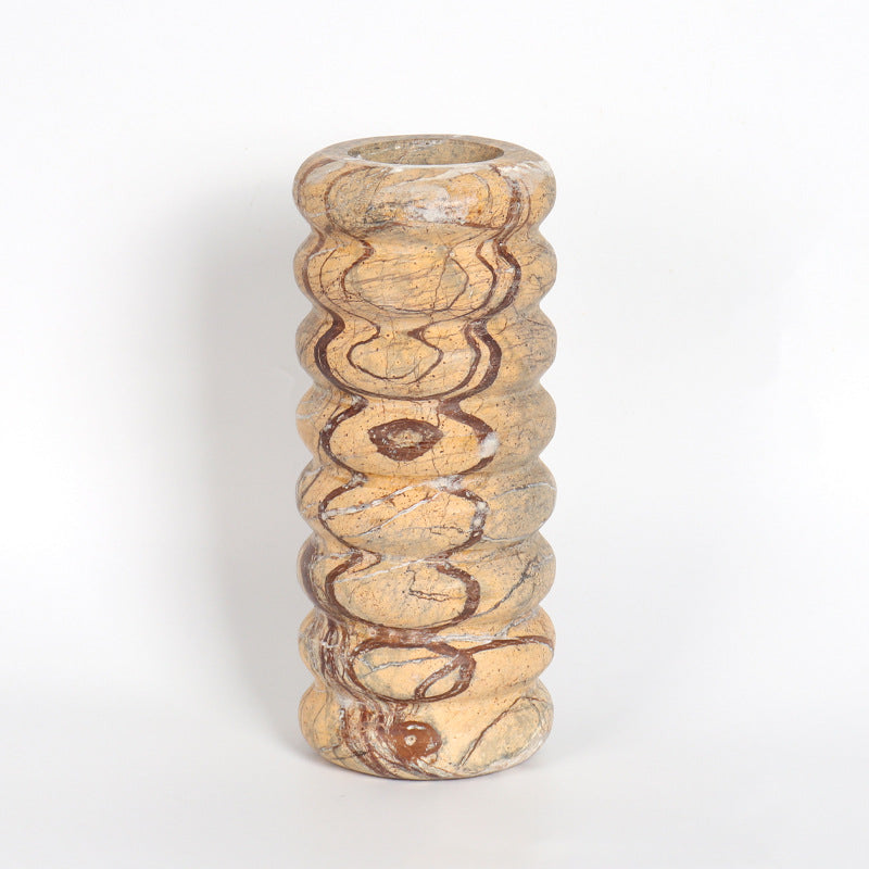 Front view of a tall cylindrical marble vase featuring a bumpy textured surface and natural earth tone patterns
