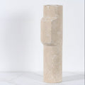 Side view of a tall cylindrical travertine stone vase showing the unique geometric protrusion and porous stone texture