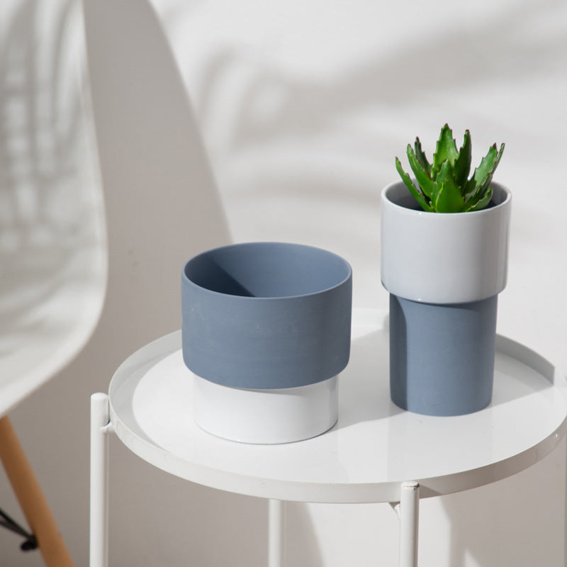 Tall bone white and slate grey ceramic planter with a small aloe vera plant on a white designer table