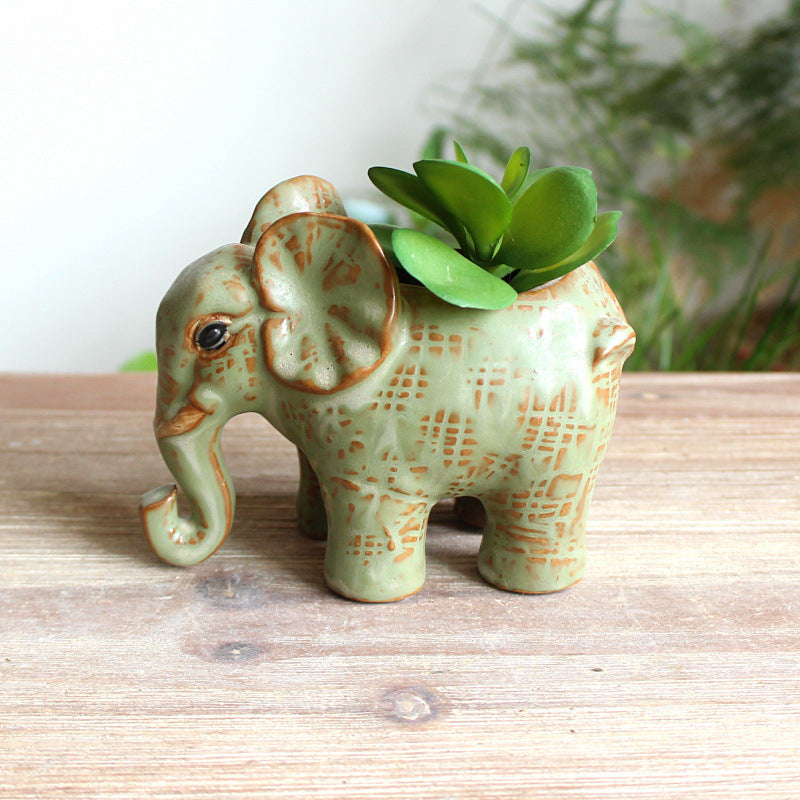 Detailed side view of an elephant shaped ceramic pot with a small green succulent