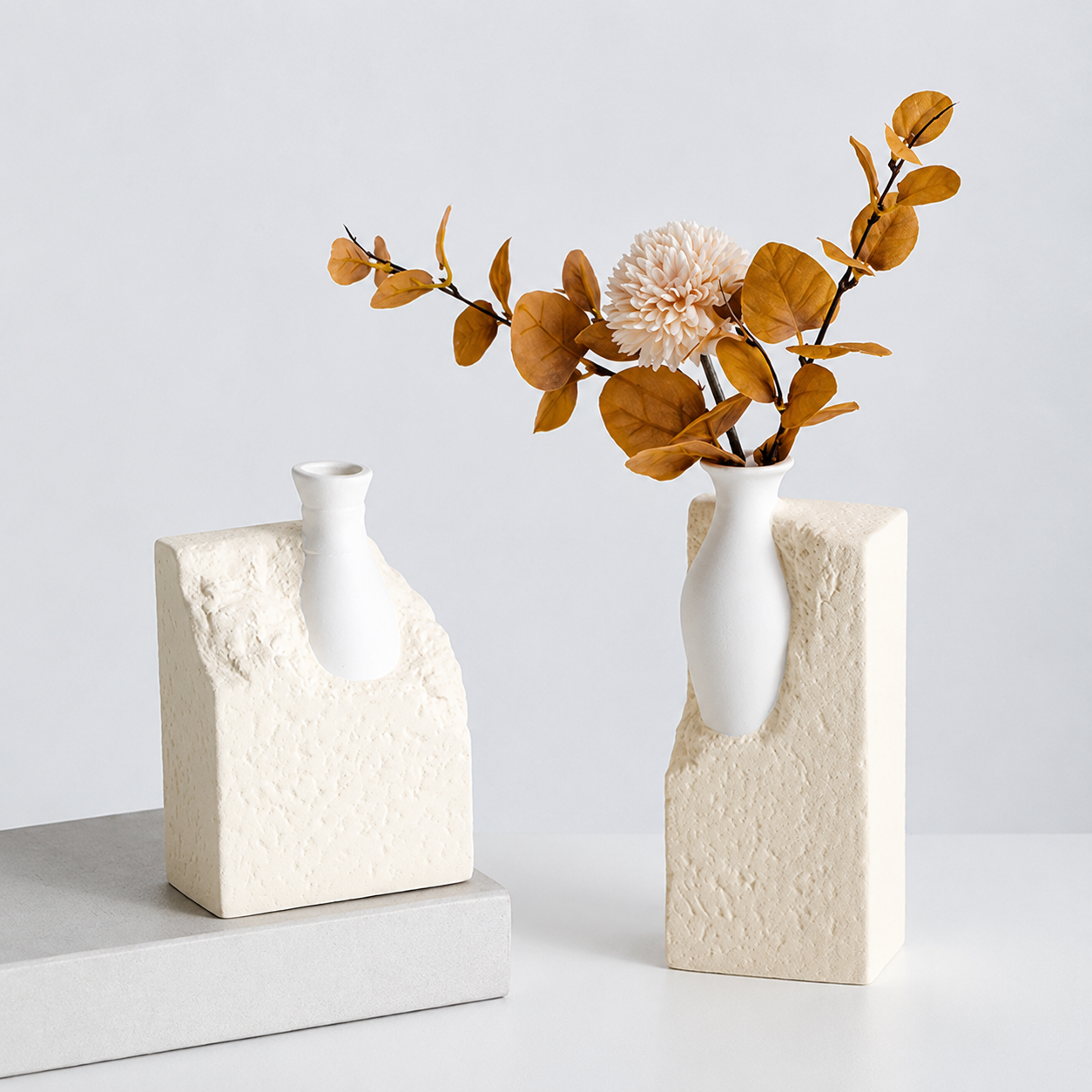 Beige abstract ceramic vases styled with warm brown foliage