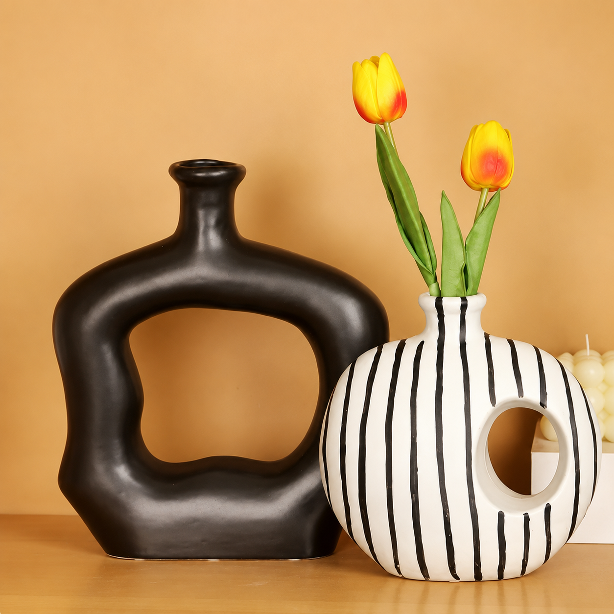Matte black and striped abstract ceramic vases styled on warm neutral background