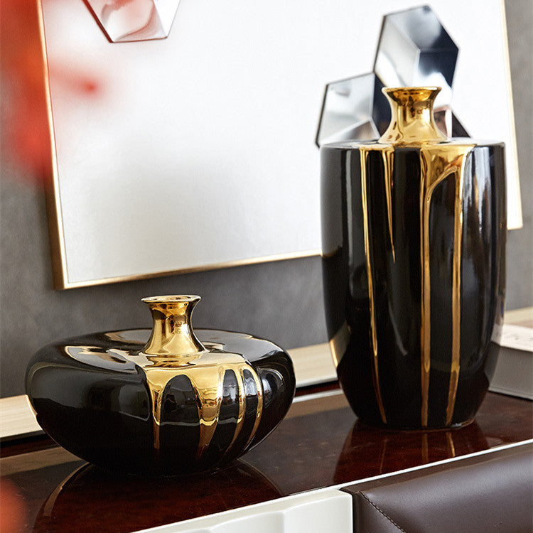 Black ceramic vase set with gold drip details displayed in elegant living room decor setting
