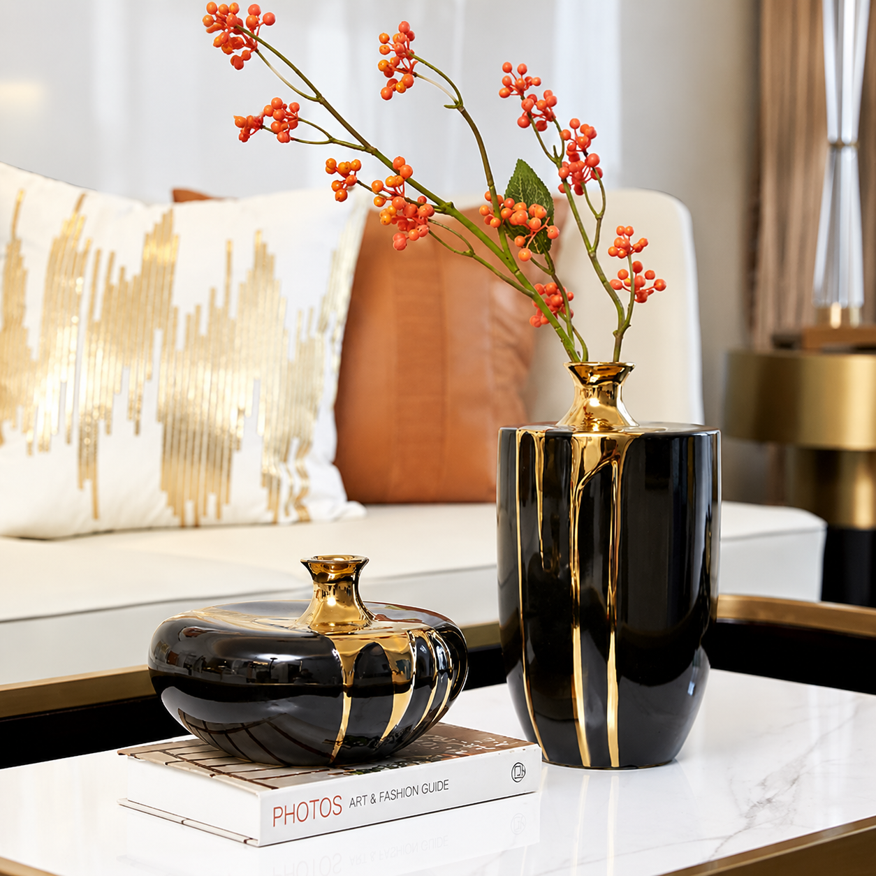 Short and tall black ceramic vases with glossy gold drip accents styled with red berry branches