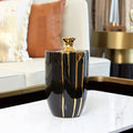 Tall black ceramic vase with gold drip accents and red berry stems in luxury living room setting