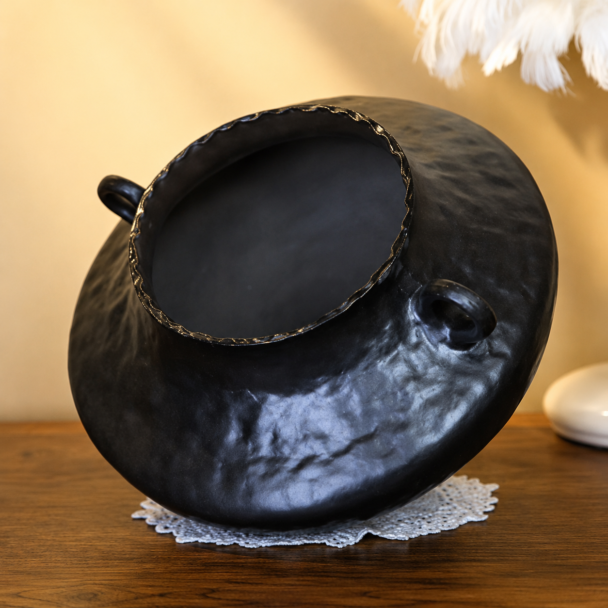 Angled view of black ceramic vase with handles showing wide opening and textured body