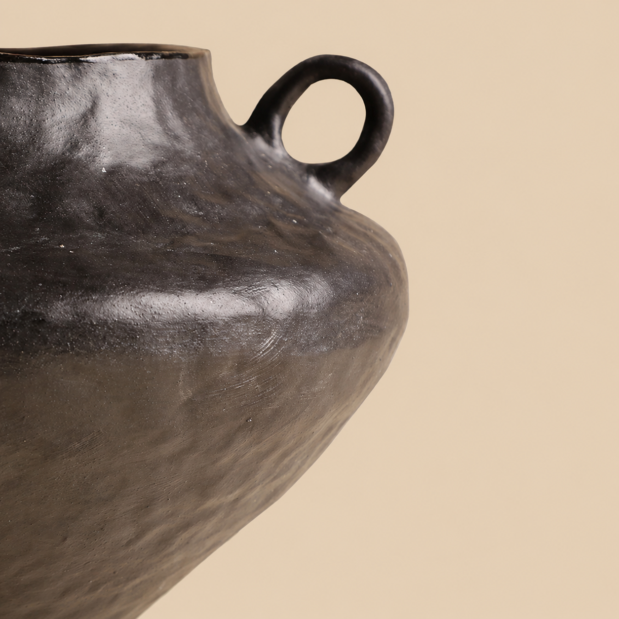 Close up of black ceramic vase handle and textured dark surface