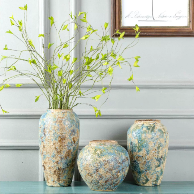 Blue gold textured ceramic vases styled with fresh green branches in a bright interior
