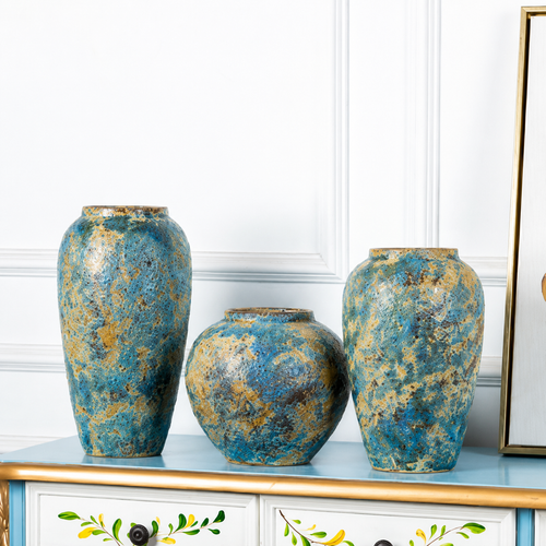 Three blue gold ceramic vases displayed together on a painted console table