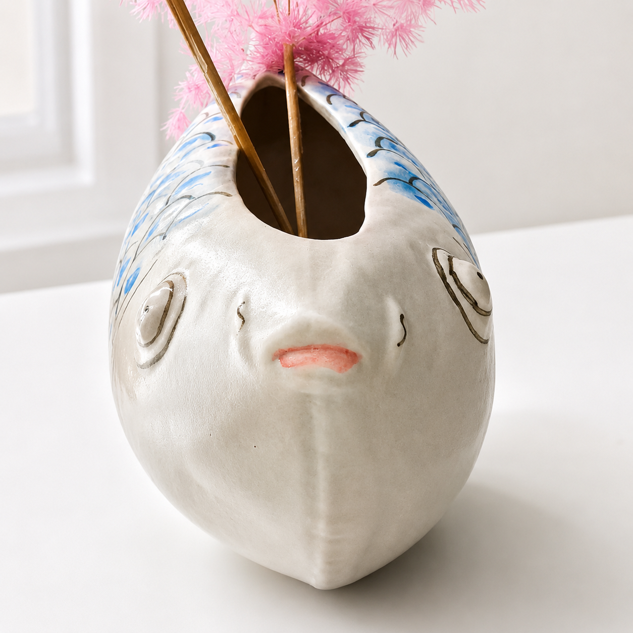 Top opening view of blue and white fish-shaped ceramic vase showing fish face details