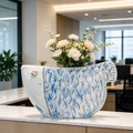 Blue and white fish-shaped ceramic vase with white floral arrangement on a marble counter