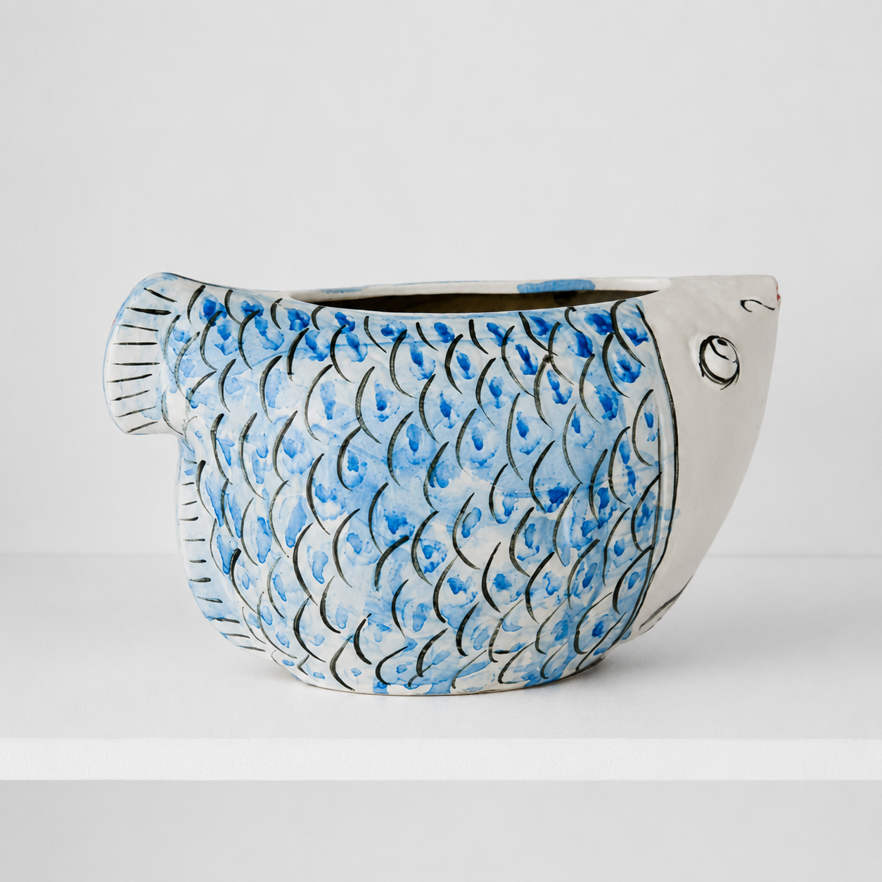Front view of blue and white fish-shaped ceramic vase on white background