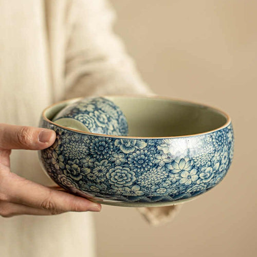 Blue and white floral ceramic bowl held by hand showing rounded serving shape