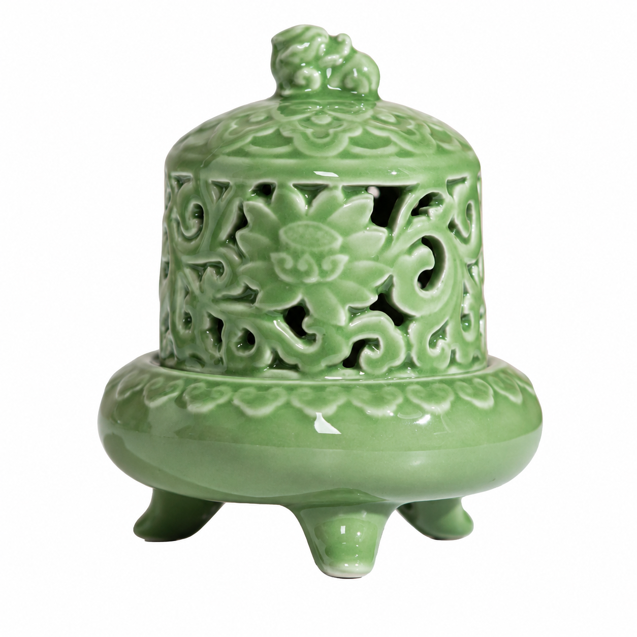 Ornate celadon green ceramic incense burner with pierced cover and three feet on white background