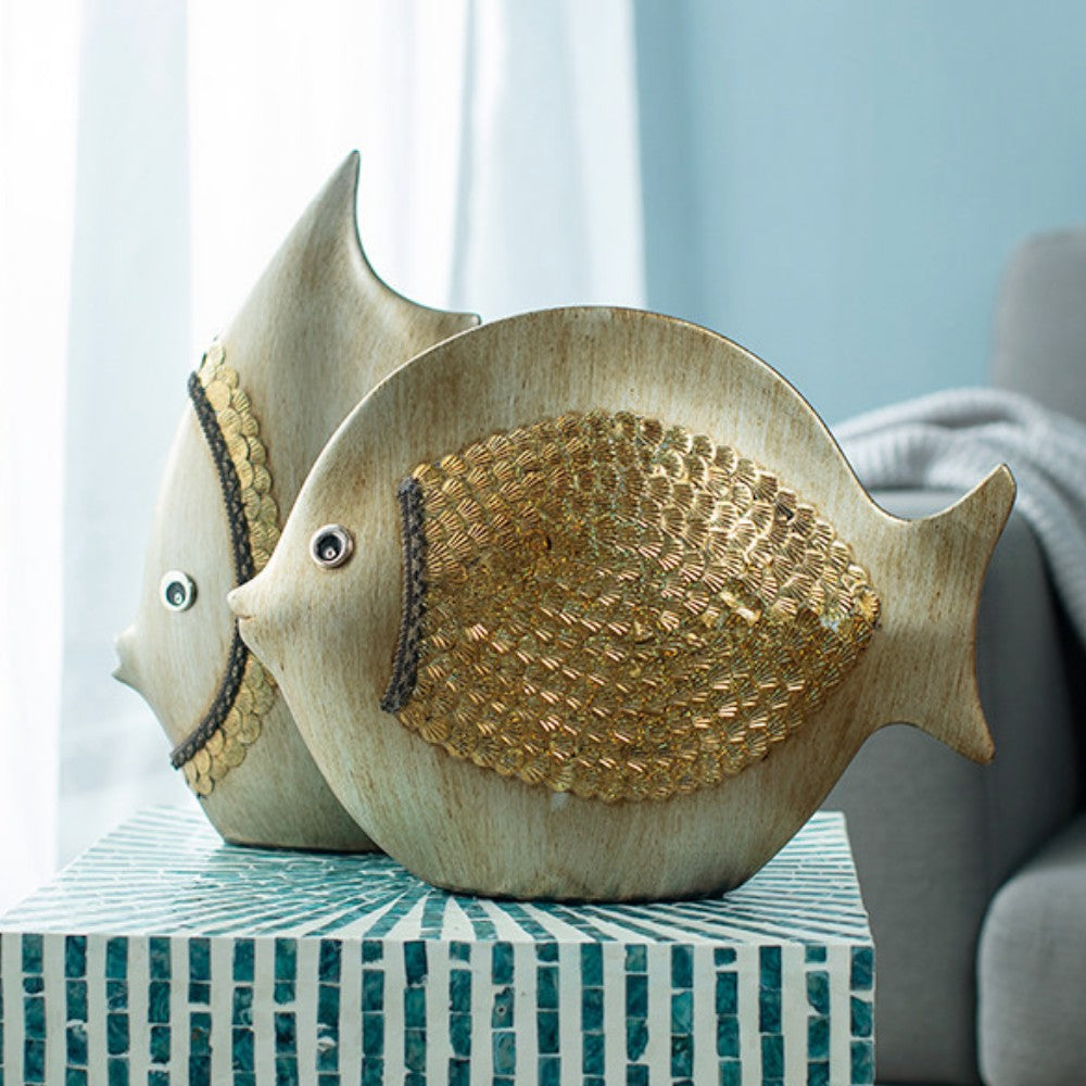 Two ceramic fish figurines styled together in a soft coastal interior