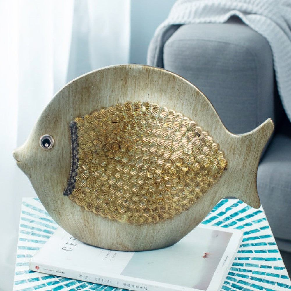Round fish statue in ceramic with textured body detail on a book