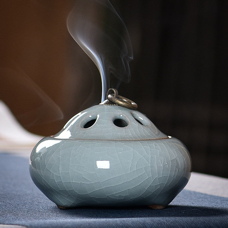 Blue Gray ceramic incense burner releasing smoke through ventilated lid
