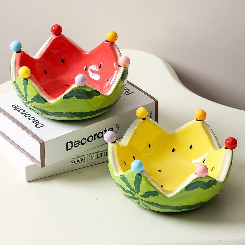 Watermelon inspired ceramic crown bowls in red and yellow displayed on stacked books