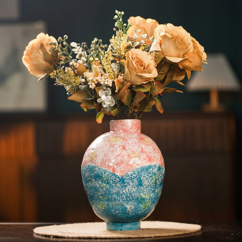 Colorful pink and blue ceramic vase with peach flowers in modern interior