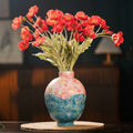 Colorful ceramic vase with red flowers styled on round table