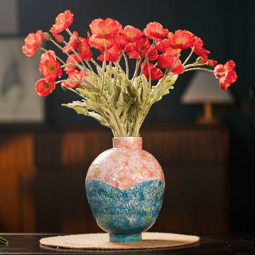 Colorful ceramic vase with red flowers styled on round table