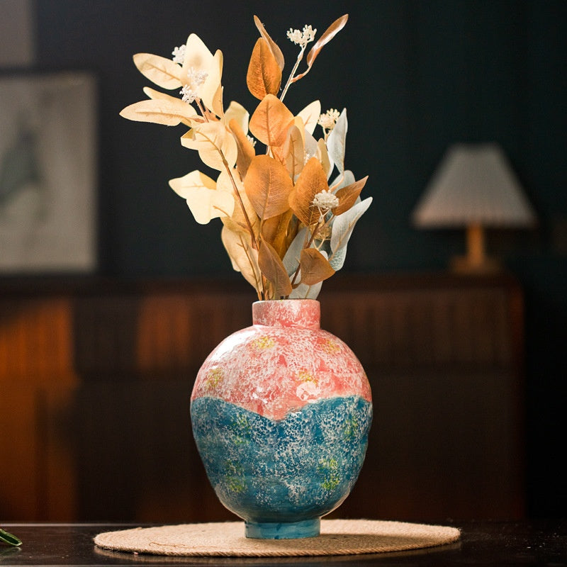 Colorful ceramic vase with dried flowers on table in warm home decor setting