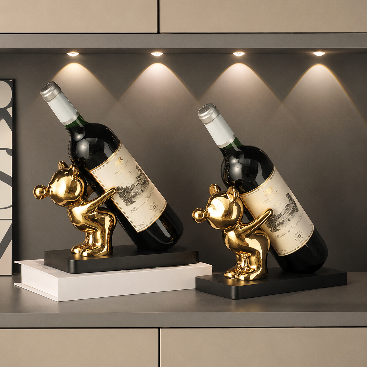 Two gold ceramic wine bottle holders with bottles styled under warm cabinet lighting