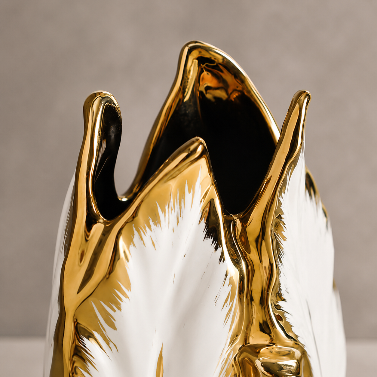 Close-up of glossy white ceramic plantain leaf vase with gold electroplated rim
