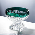 Angled view of emerald green fluted glass centerpiece bowl on clear pedestal base
