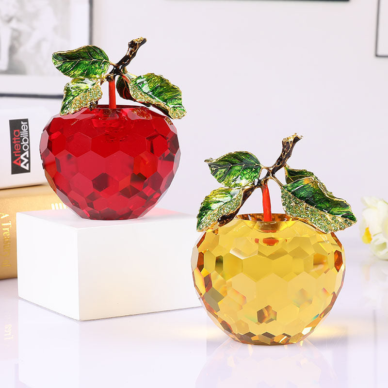 Two crystal apples, one red and one yellow, on a white surface