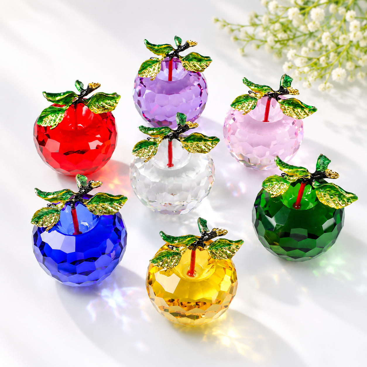 Colorful crystal apples on a white background with flowers.