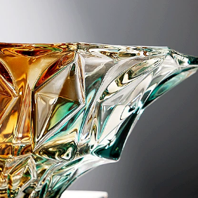 Close-up detail of geometric faceted glass bowl with teal amber gradient and reflective texture