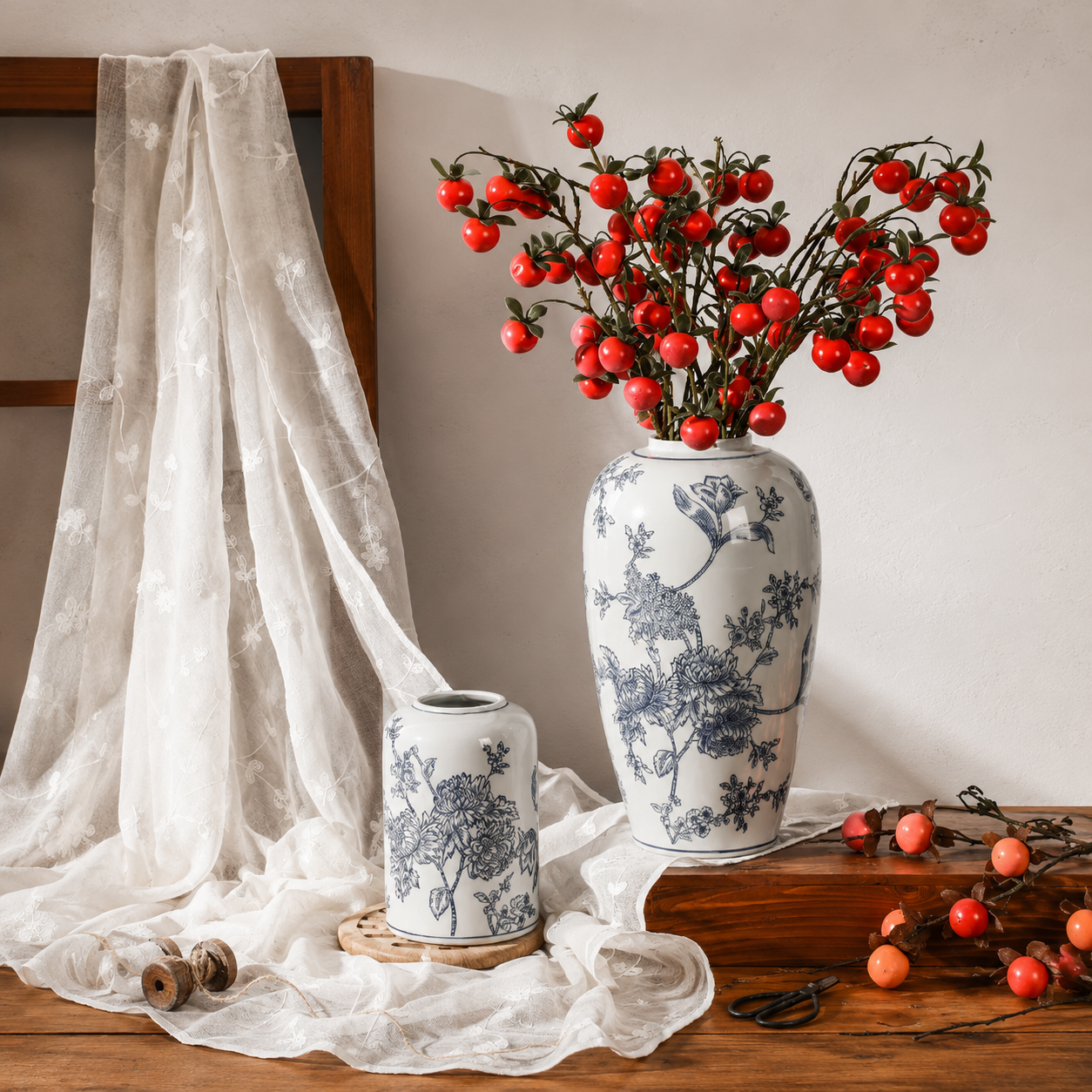 Blue floral ceramic vase with orange berry branches on a console table
