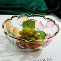 Floral embossed glass centerpiece bowl with gold scalloped rim filled with green grapes