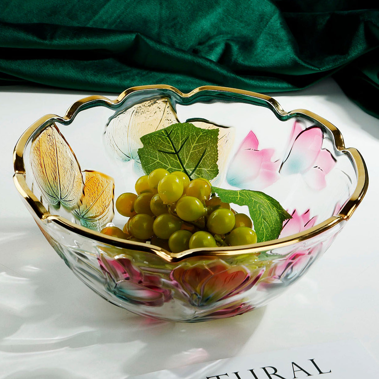 Floral embossed glass centerpiece bowl with gold scalloped rim filled with green grapes