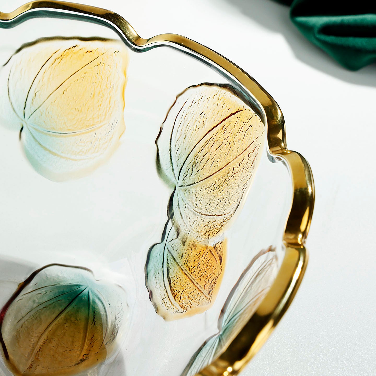 Close up of gold rimmed glass bowl with embossed yellow and teal floral details