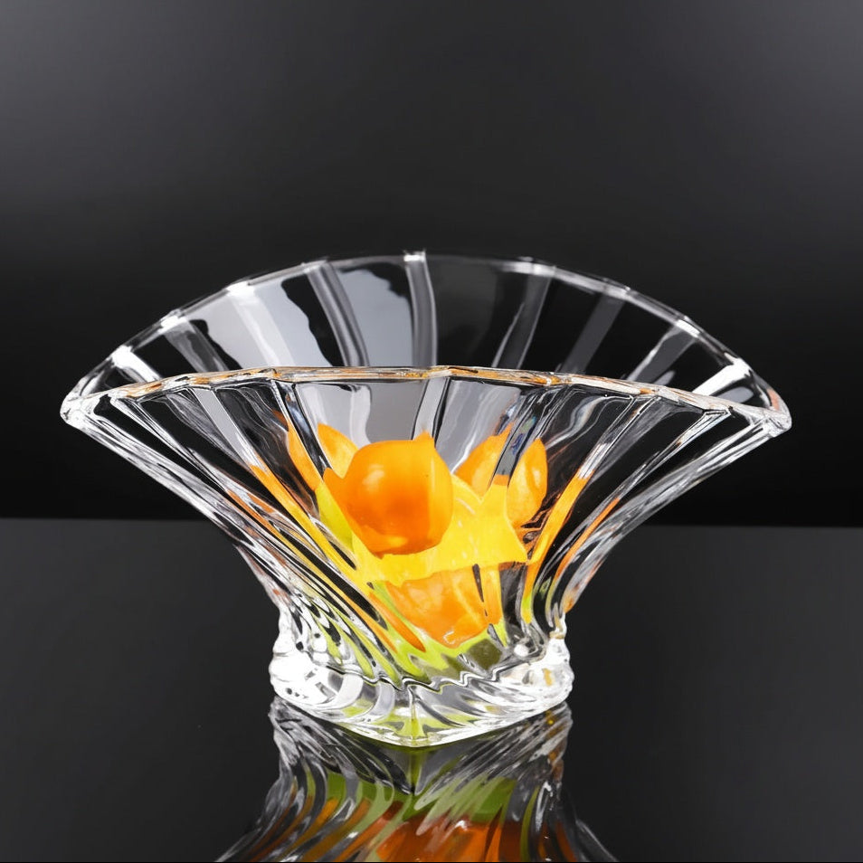 Clear flared glass serving bowl with orange fruit on a dark background