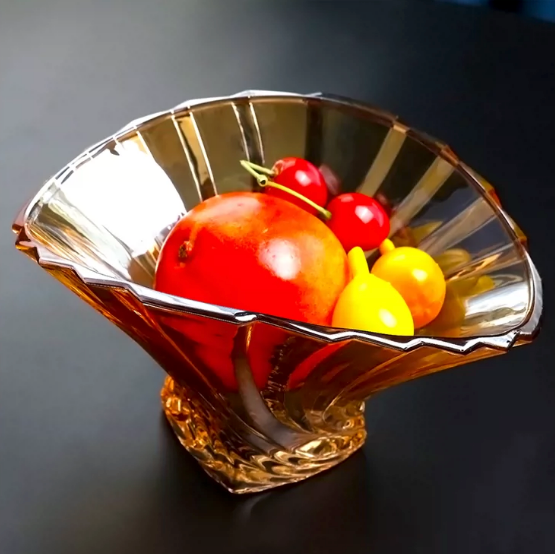 Amber fluted glass centerpiece bowl filled with assorted fruit on a dark tabletop