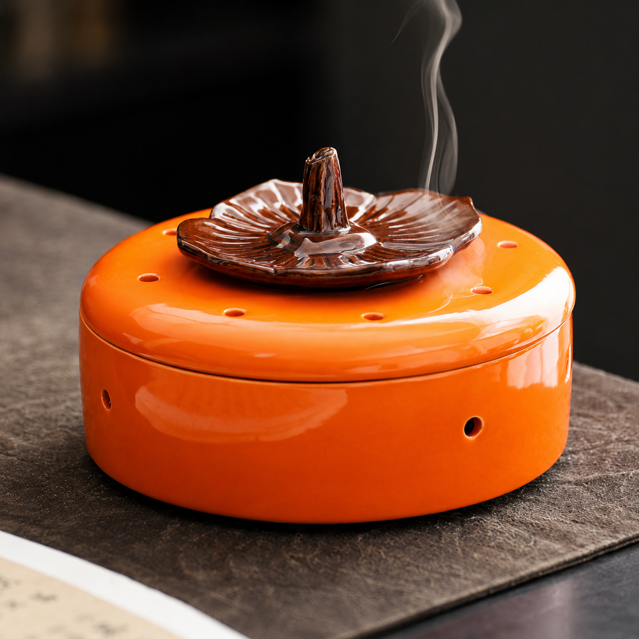 Orange ceramic incense burner with brown floral lid and gentle smoke for ritual decor