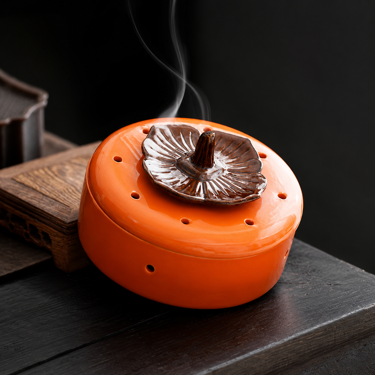 Orange ceramic incense burner on dark wood table with smoke, ideal for zen home decor