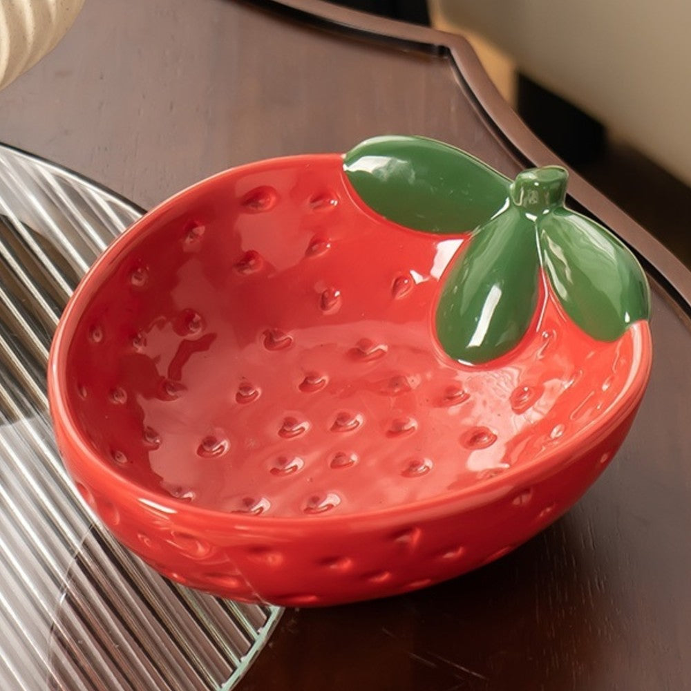 Glossy red strawberry ceramic bowl displayed on a dark wood table