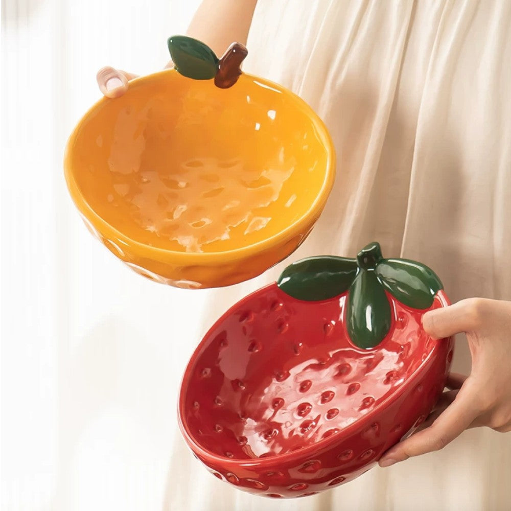 Yellow citrus bowl and red strawberry bowl shown together in hand