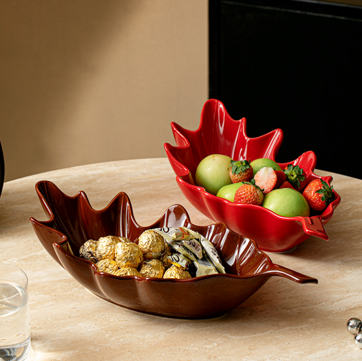 Red and brown leaf shaped ceramic serving bowls with snacks and fruit