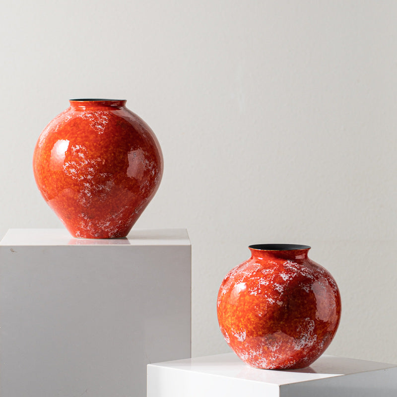 Two glossy orange ceramic vases displayed on white pedestal blocks