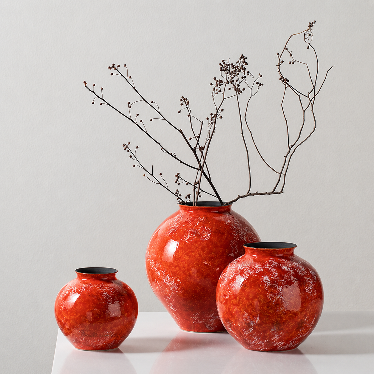 Three glossy orange ceramic vases in small medium and large sizes