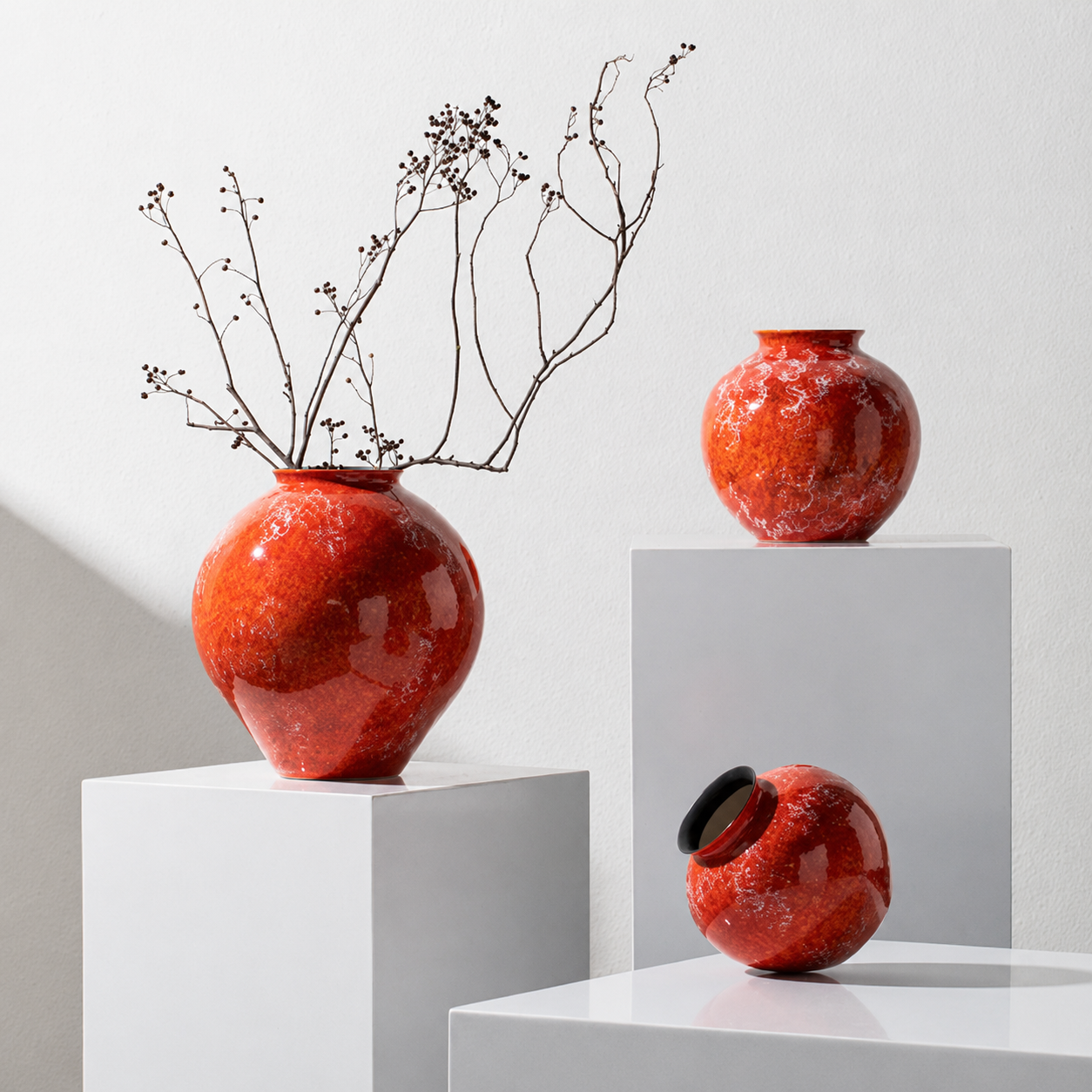 Orange ceramic vases displayed on white geometric pedestals